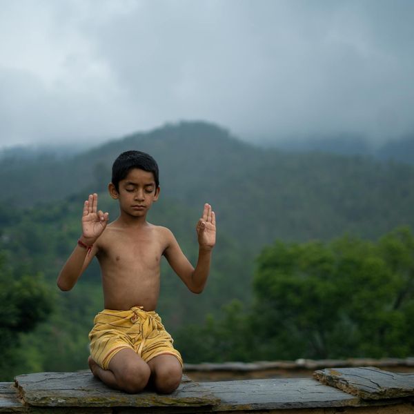 Person meditating outdoors with a beautiful natural landscape background.
